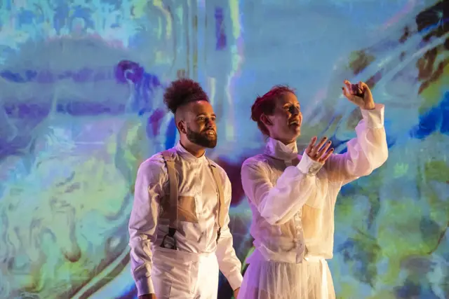 Curie Curie: two dancers before a swirling blue and gold projection