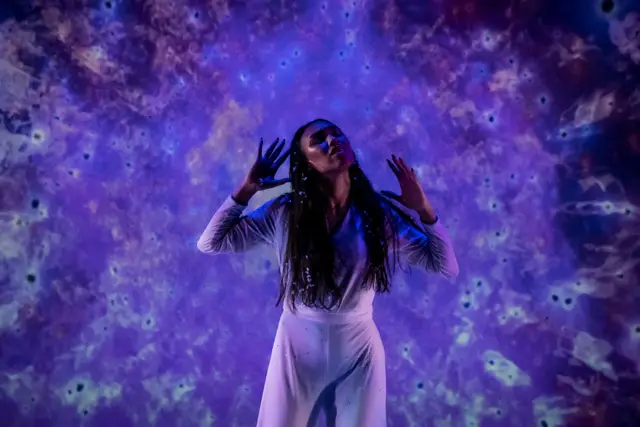 The Passage: a dancer in white surrounded by a projected violet field of light