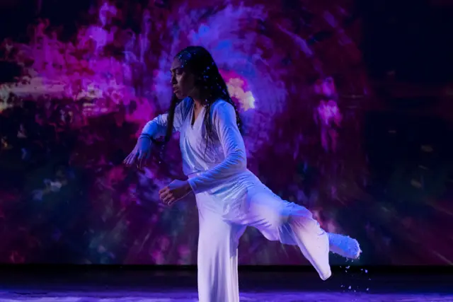 The Passage: a dancer mid-turn before a projected purple swirl