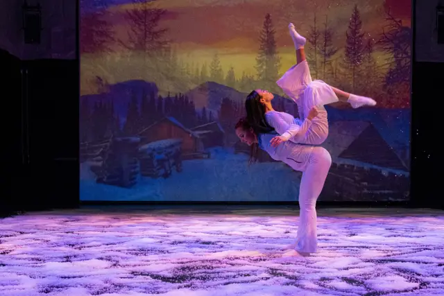 The Passage: a dancer in a backbend before a projected snowy cabin at sunset